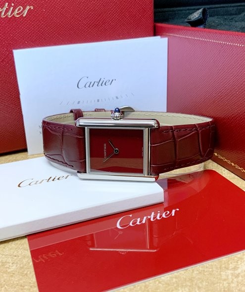 The Cartier Tank Must Large Model (WSTA0054) features a deep red dial surrounded by a polished stainless steel “Tank” case.